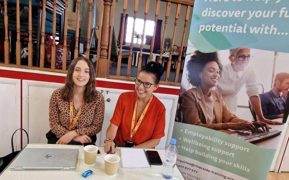 Two women sat behind a table 