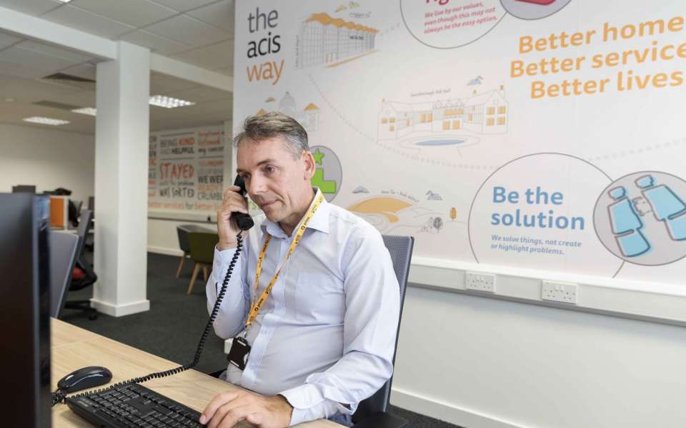 Acis employee sitting in front of computer on the telephone