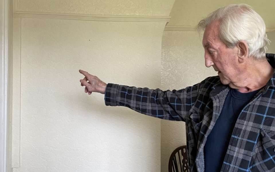 Elderly man pointing at cream wall