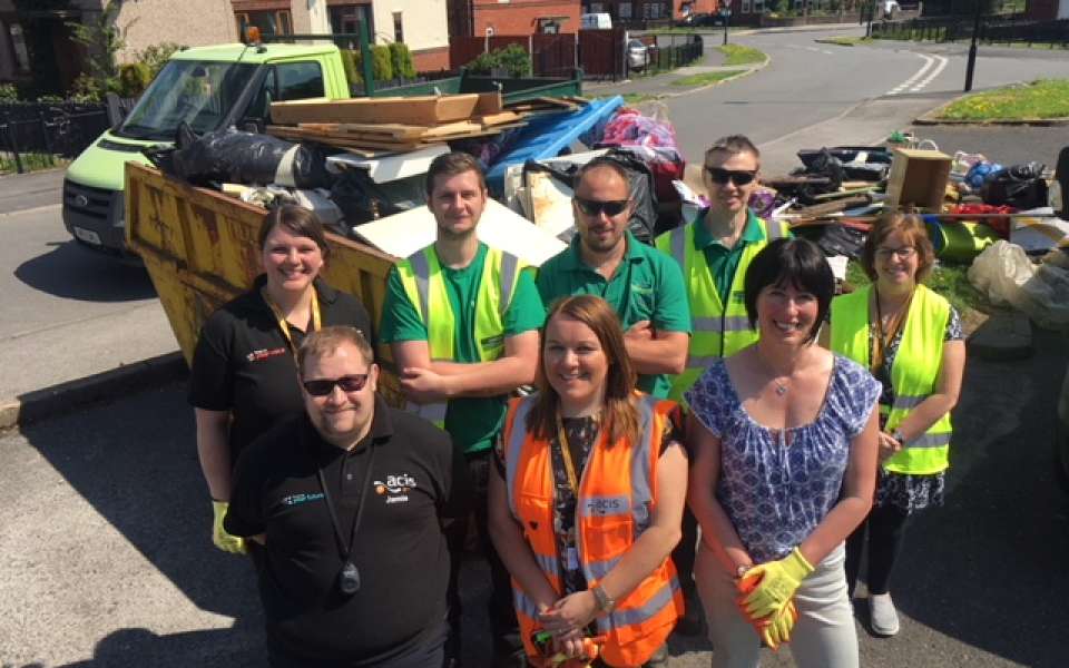 Group of people standing in front of full skips