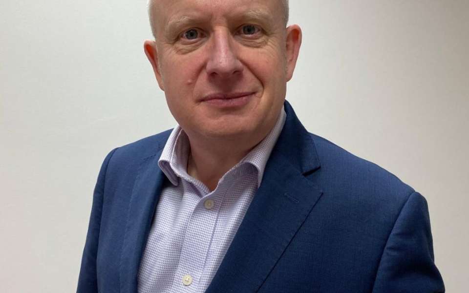 Headshot of Mark Jones in a blue suit and light blue shirt