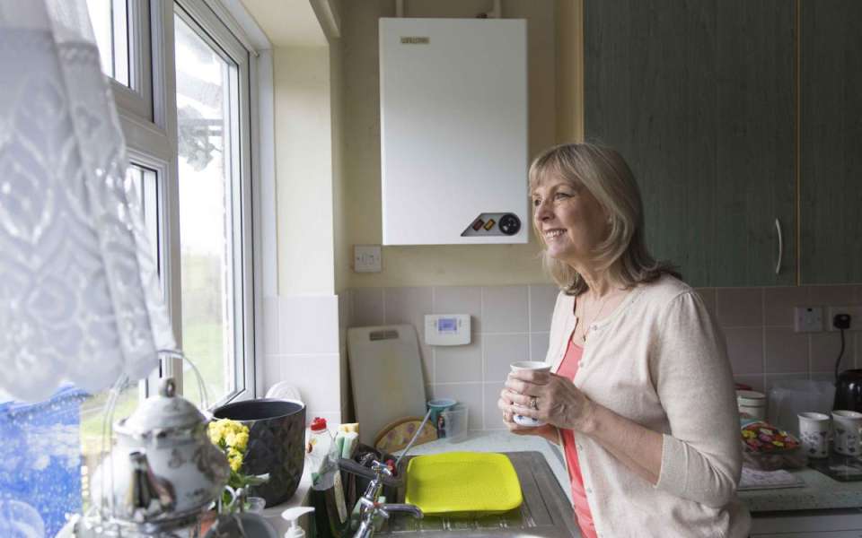 Person standing in kitchen holding a mug looking out of the window