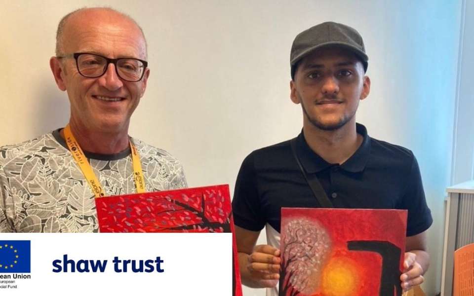 Two people holding up their paintings for the camera