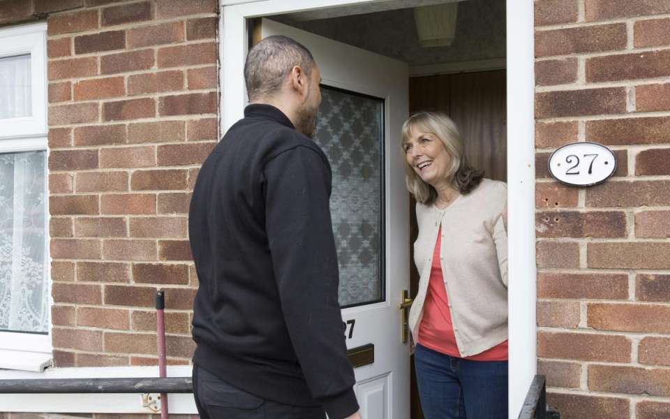 Woman greeting man at her front door