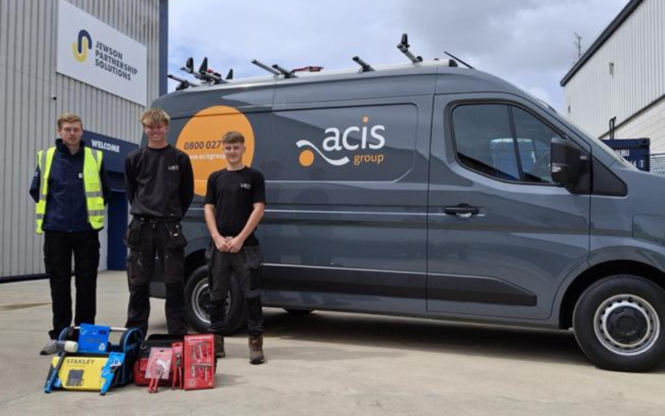 Acis Group and Jewson employees stood in front of an Acis Group van parked outside of Jewsons showing the tools donated to apprentices
