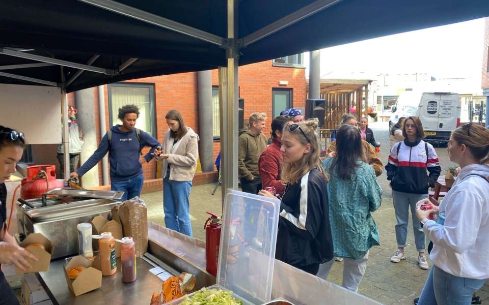 students stood chatting and getting burgers from food truck