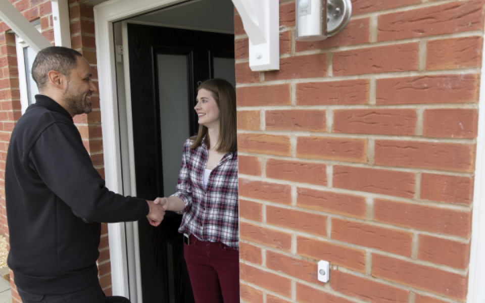 An engineer shaking a lady's house on her doorstep.