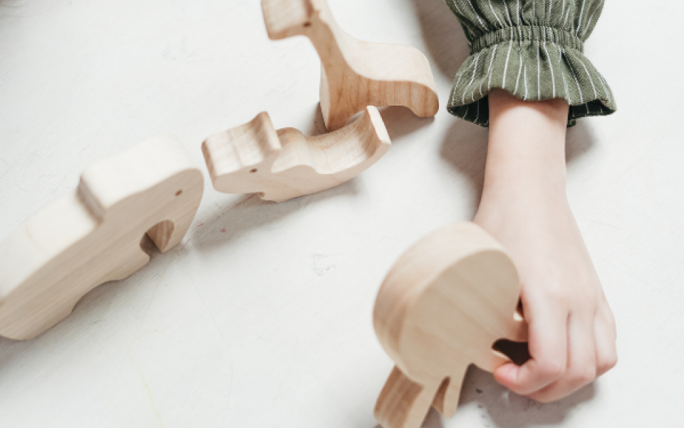 A hand holding childrens' wooden animal toys