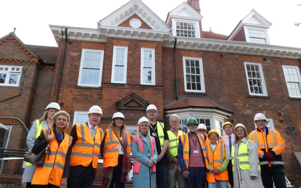 A photo of people stood in the foreground with Grange house in the background