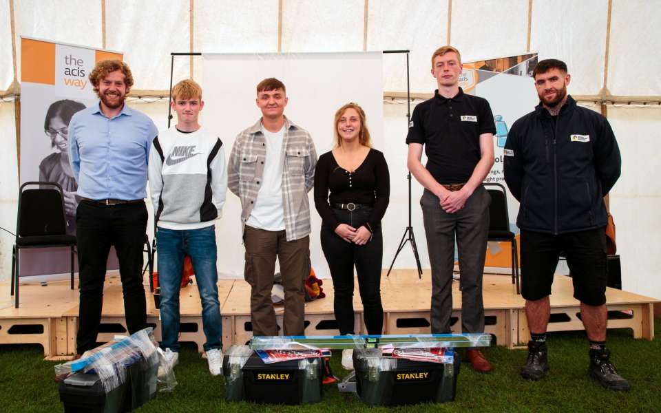 Six people stood smiling with tool kits
