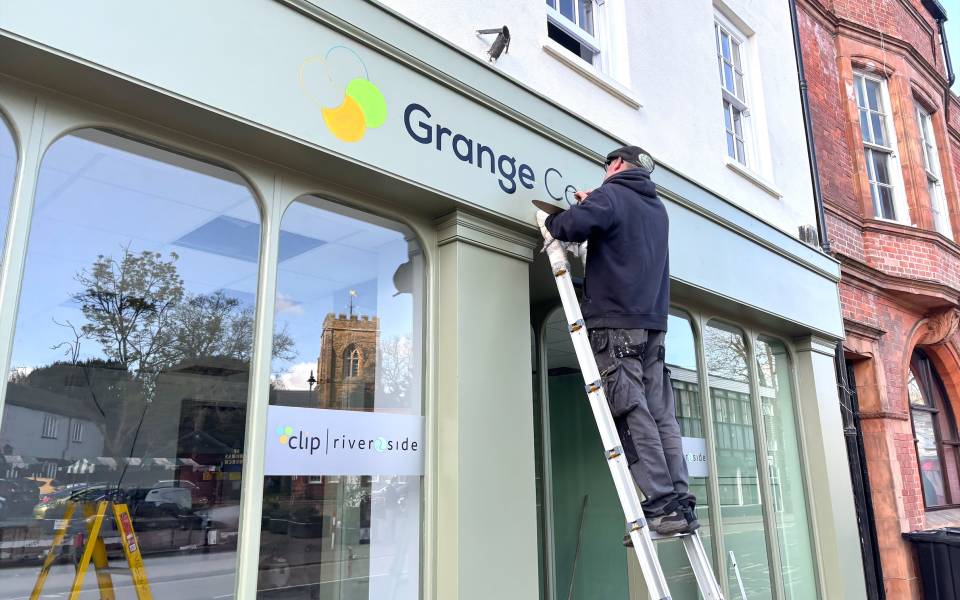 A man paints a sign on a shop front