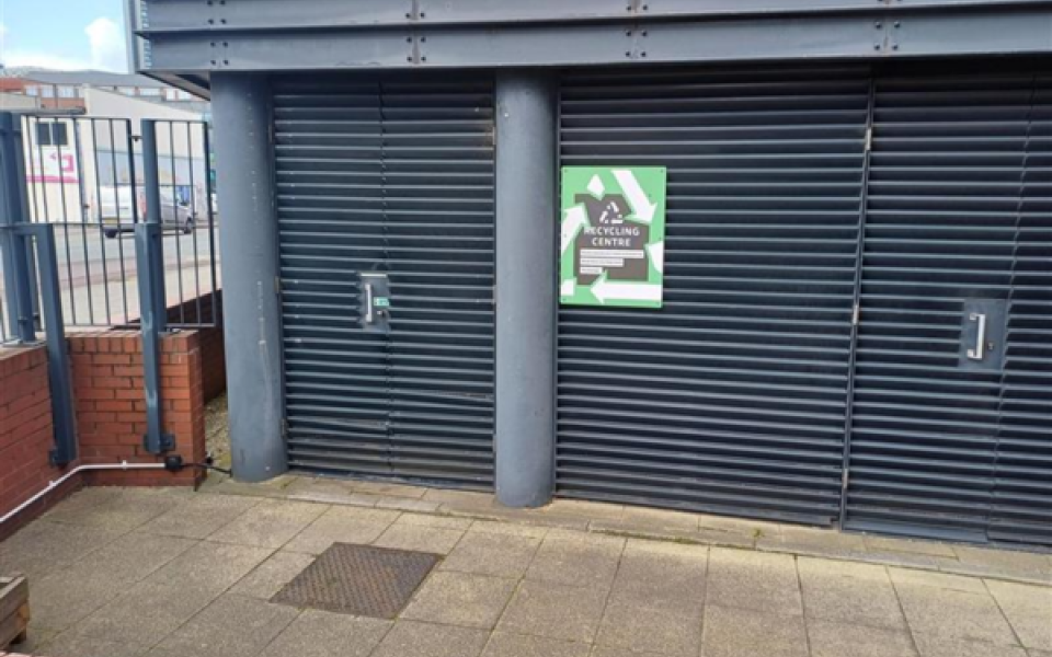 A door to a bin store with a sign saying recycling centre